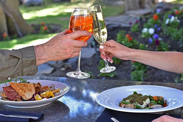 Happy Hour at Buffalo Mountain Lodge 1 Two people toast with wine glasses over a gourmet meal at an outdoor dining table