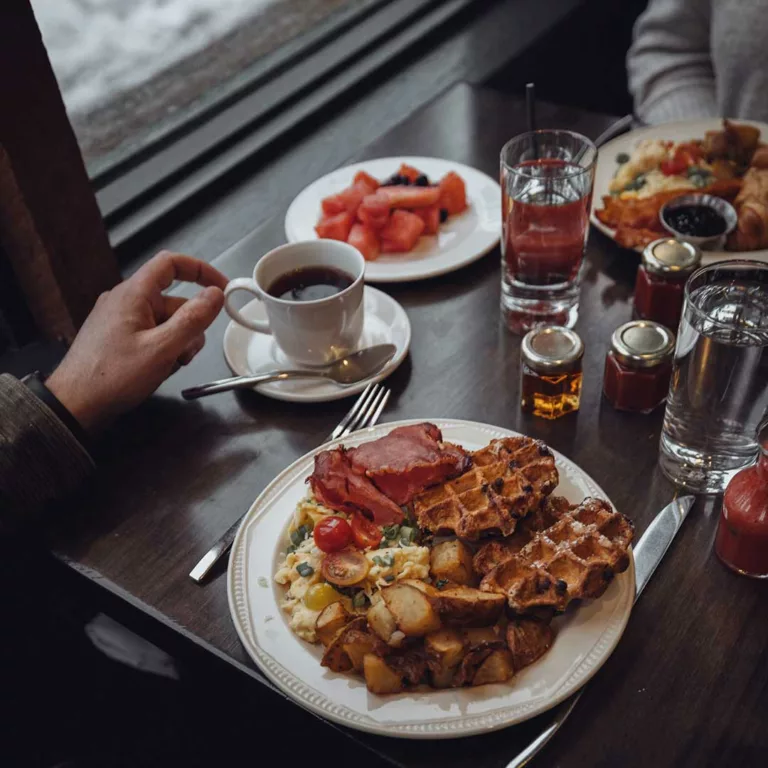 A hearty breakfast spread at a cozy restaurant, featuring waffles, scrambled eggs and roasted potatoes