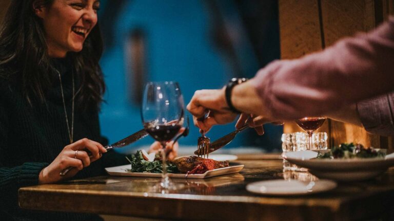 A couple enjoys a cozy dinner with wine at a rustic restaurant at Emerald Lake